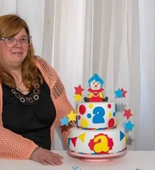 Se puede agregar está foto que diga está soy yo?. foto de Mariel junto a una torta temática de payaso de dos pisos